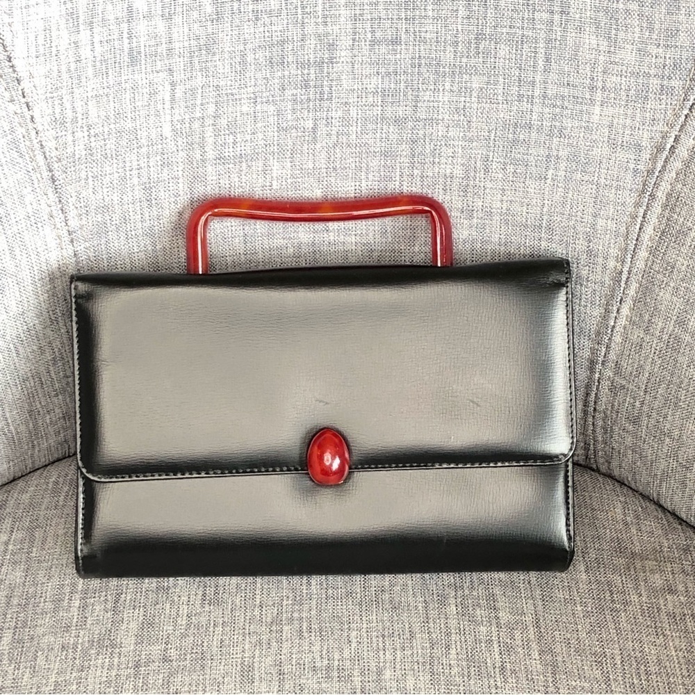 Vintage black faux leather handbag with red Bakelite handle and buckle